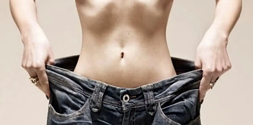 Person showing looser jeans after losing weight.